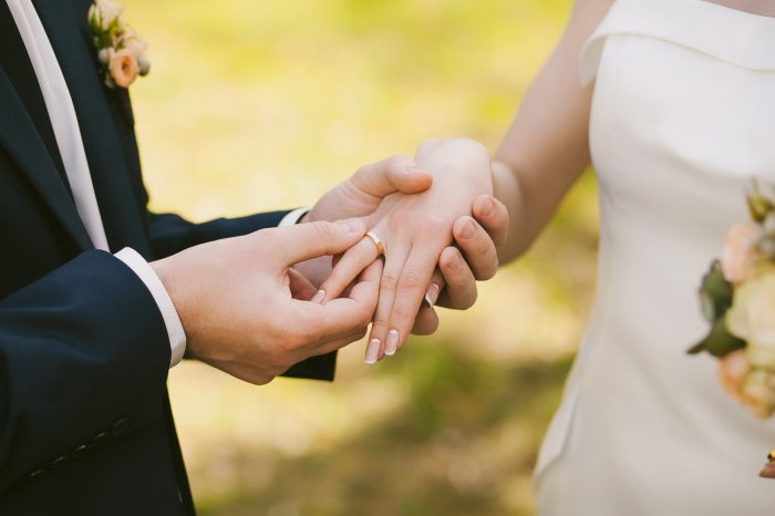 Жених надевает кольцо на палец невесты