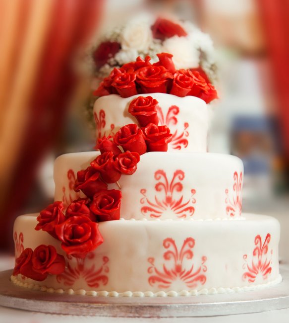 Белый свадебный торт, украшенный красными цветами