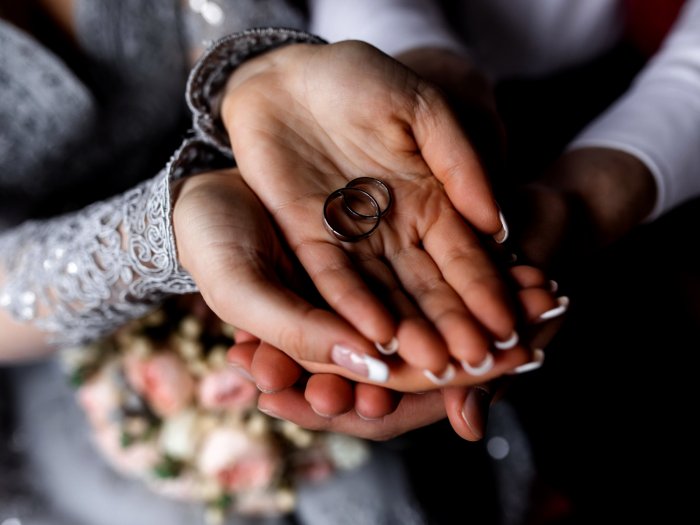 Жених с невестой держат обручальные кольца в руках